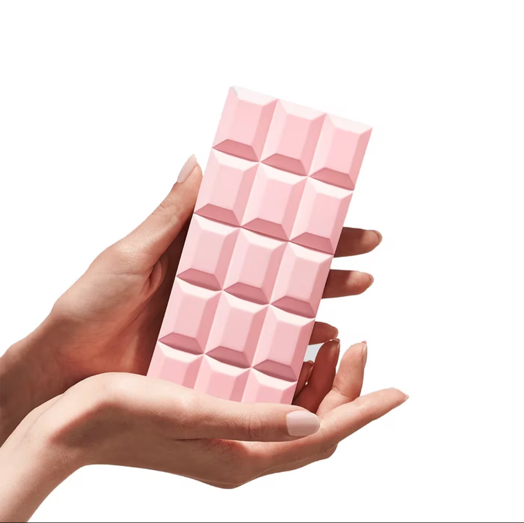 Hand holding a pink chocolate bar with a geometric pattern on a white background